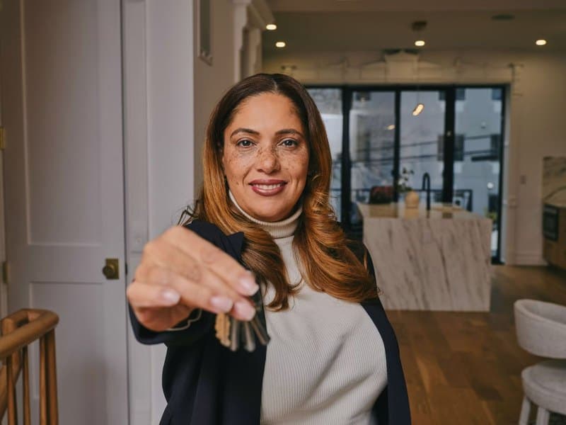 A Peace of Mind Realty agent holding out the keys to a property